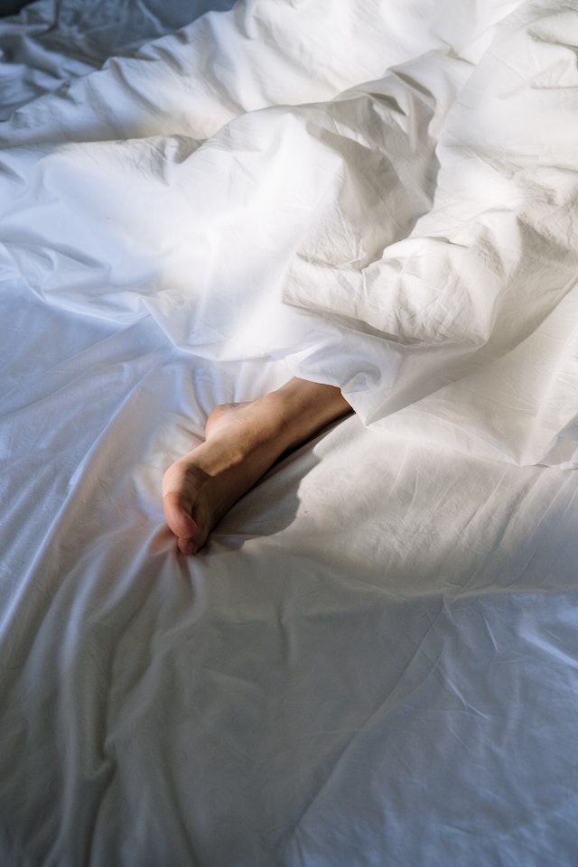 Person sleeping soundly under a blanket, foot exposed 